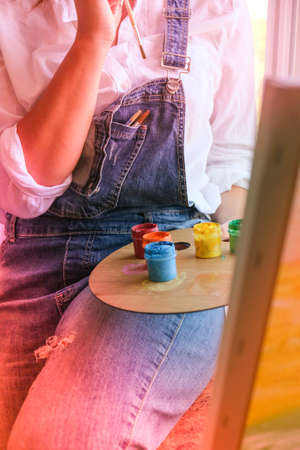 Creative painter in working process. Artist workplace, hobby, craft tools. Artist female canvas painting. Professional young woman painter draws in the workshop. Leisure activity. Art at homeの写真素材