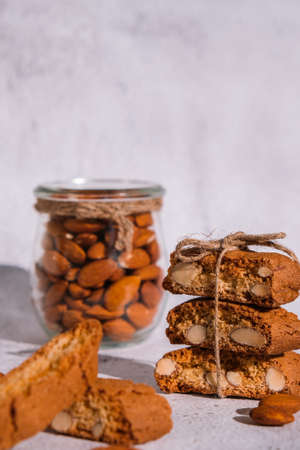 Traditional Italian cantuccini cookies with almonds in glass jar. Sweet dried biscuits. Homemade fresh Italian cookies cantuccini stacks and organic almond seeds. Healthy organic nutritionの写真素材