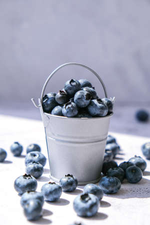 Blueberries in a small Bucket on concrete background. Healthy organic seasonal fruit background....