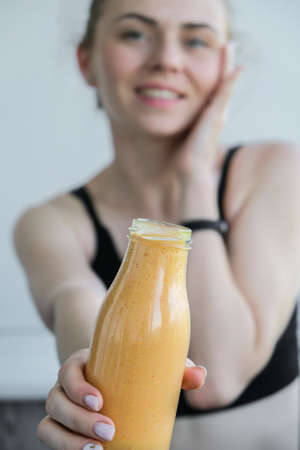 Young millenial blond woman drinking vegan smoothie drink detox. Woman doing yoga exercises at home. Clean eating, weight loss, healthy dieting food concept. Stay healthyの写真素材