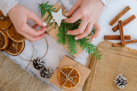 Woman making Box with New Year's gifts, wrapped in craft paper and decorated with fir branch. Holidays and Gifts concept. Handmade Eco friendly alternative green Christmas presents zero waste Sustainable lifestyle Top view Flat layの写真素材