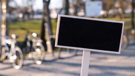 Empty mockup template Blackboard label against defocused background of bicycle sharing station....