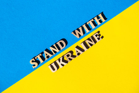 Ukrainian national flag made of paper. STAND WITH UKRAINE text. Stop War. The concept of ending the...
