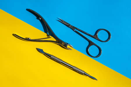 Set of disinfected manicure or pedicure tools on yellow and blue background. Cuticle pushers and...
