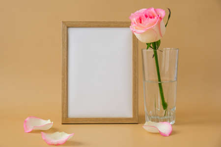 Mockup Wooden frame with Empty white paper blank and delicate pink roses on beige background....