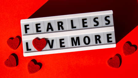 Lightbox with text FEAR LESS LOVE MORE. Motivational Words Quotes Concept with red hearts. colorful red background. Minimal creative concept. Inspirational phraseの写真素材