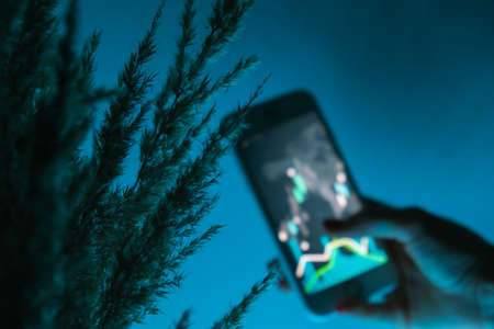 Defocused Woman holding mobile phone, block chain with graph of stock market background, cryptocurrencies or bitcoin concept. night light. Futuristic stock exchange with general info shown on screenの写真素材