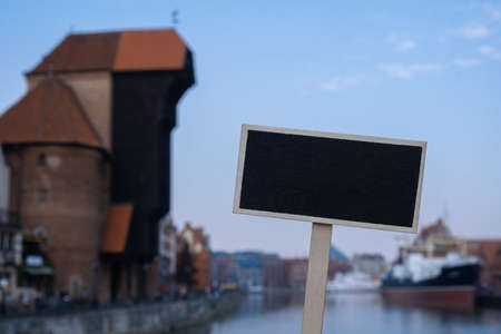 Empty mockup template Blackboard label against Gdansk beautiful old town over Motlawa river. The Zuraw Crane and colorful gothic facades of the old town in Gdansk, Poland. Visit Gdansk historical capital of Polish Pomerania with beautiful architecture Travel to Polandの写真素材