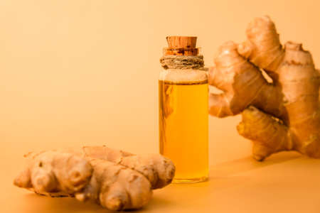 Glass bottle of essential ginger oil, ginger root on beige background. Healthy food eating concept. Zingiber officinale essential oil. Earth tones Natural cosmetics ingredients for skincare, body and hair care. copy spaceの写真素材