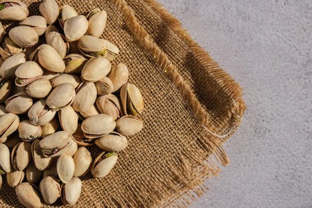 Pistachios in burlap sack on concrete table. Organic pistachios. Vegan Healthy food high protein....