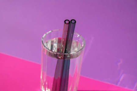Reusable glass Straws in Glass with water on purple violet background Eco-Friendly Drinking Straw Set with cleaning brush. Zero waste, plastic free conceptの写真素材