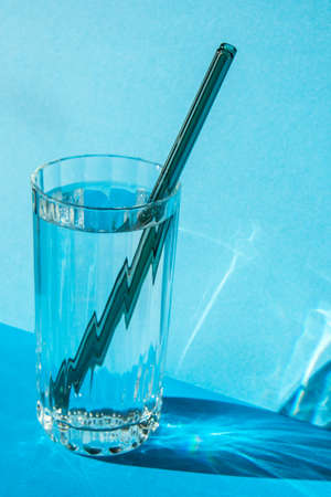 Reusable glass Straws in Glass with water on blue background Eco-Friendly Drinking Straw Set with cleaning brush. Zero waste, plastic free conceptの写真素材