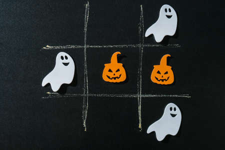 Creative tic tac toe game made of halloween decorations. Ghost bat pumpkin Autumn party concept...