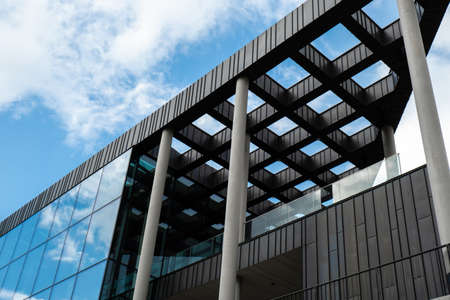Modern office building exterior with glass facade on clear sky background. Transparent glass wall of...
