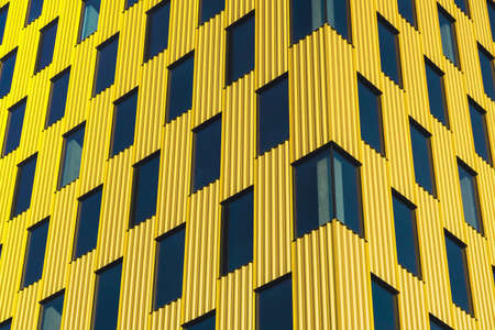 Modern office building exterior with glass facade on clear sky background. Transparent glass wall of office building with yellow decoration. Element of facade of modern European building Commercial office buildings. Abstract modern business architectureの写真素材