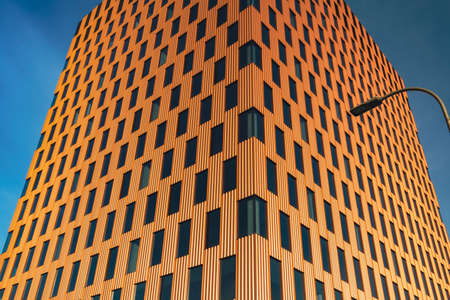 Modern office building exterior with glass facade on clear sky background. Transparent glass wall of office building with orange decoration with lantern. Creative Photo Element of facade of modern European building Commercial office buildings. Abstract modern business architectureの写真素材
