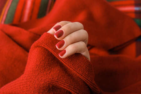 Woman manicured hands, stylish red nails, copy space. Red sweater Closeup. Winter or autumn style of nail design concept. beauty treatment. Fall nailsの写真素材