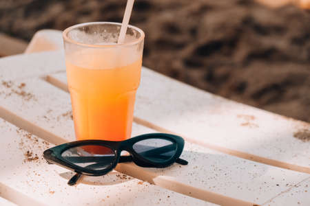 Fresh cold mango smoothie cocktail on tropical beach bright sand. Summer sea vacation and travel...