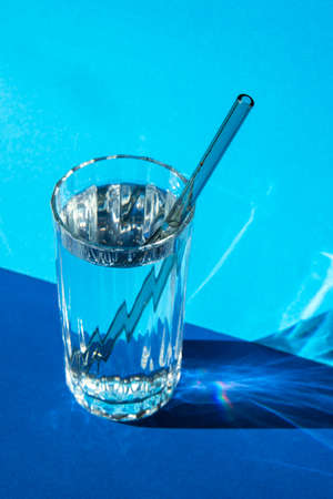 Reusable glass Straws in Glass with water on blue background Eco-Friendly Drinking Straw Set with...