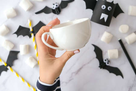 Female hands paint on white cup scary jacks face DIY for kids Halloween home activities Holiday art children craft Handmade decorations. Step by step Socially distanced at home Idea for art classの写真素材