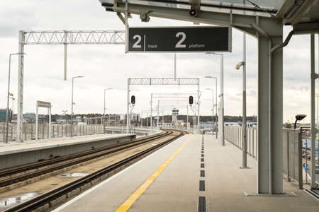 Walk way in train station with no people. Empty Passanger train railway station platform. Sign board...