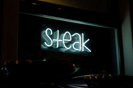Steak inscription in neon lights at night. Electric sign at night nightlife concept. Modern fluorescent life style luminescent. LED light sign textの写真素材