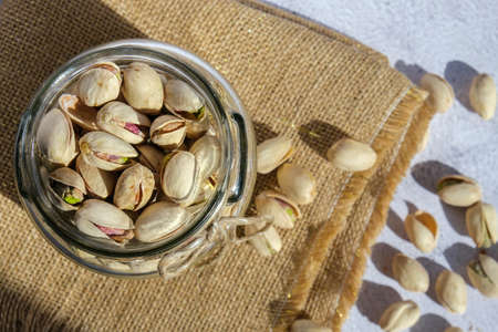 Pistachios in glass jar on concrete background. Organic pistachios, healthy food. Heap or stack of...