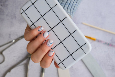 Stylish blue female nails holding mobile phone. smartphone technology. social media. Modern stylish...