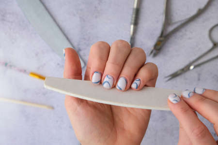 Professional stylish trendy blue Hardware Manicure. Procedure for the preparation of nails. Cuticle Pusher Remover. Nail file scissors Top view flat lay. Do manicure by yourself staying at home. self care. Spa, beautician advertisement.の写真素材