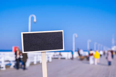 Blank Black billboard against Crowds of tourists The Sopot Pier in the city on the Baltic Sea. Empty mockup template Visitors walking The pier is the longest wooden pier in Europe. Blackboard label Sopot resort in Poland. Sign in front of Wooden pier, molo with marina and beach. Sopot is major tourist destination in Poland. Copy space for textの写真素材