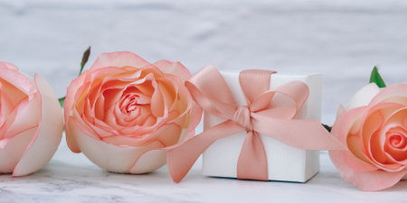 Gift box with tied ribbon bow pink roses on pink background. Greeting card. Present for springtime holidays Copy space for text.の写真素材