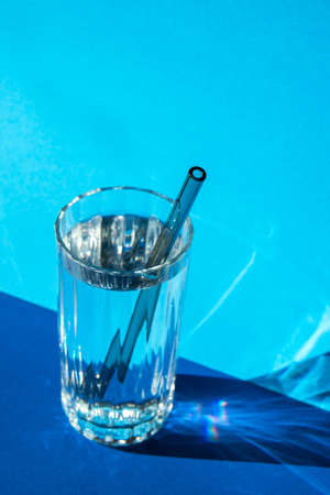 Reusable glass Straws in Glass with water on blue background Eco-Friendly Drinking Straw Set with cleaning brush. Zero waste, plastic free conceptの写真素材