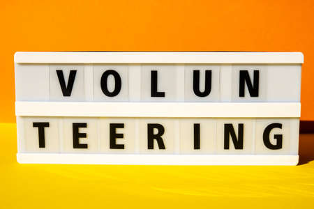 Lightbox with text VOLUNTEERING. Motivational Words Quotes Concept. colorful yellow background. Minimal creative concept. Donation supportの写真素材