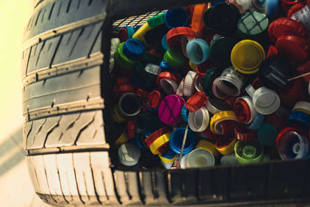 Public place collecting in car tire full of colorful plastic bottle cups, handful of waste of plastic lids. Recycling. Collecting bottle caps. Environment concept plastic bottle cap that is left from bottles collected to be recycled into other items for reuseの写真素材