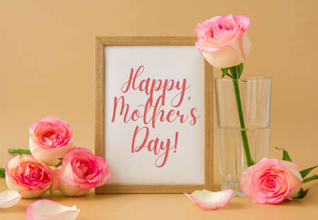 Mockup Wooden frame with text HAPPY MOTHERS DAY on delicate pink roses on beige background. Minimal trendy composition. Romantic pastel pink rose flowers. Neutral earth tonesの写真素材
