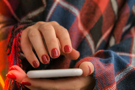 Stylish red female nails holding mobile phone. smartphone technology. social media. Modern Beautiful...