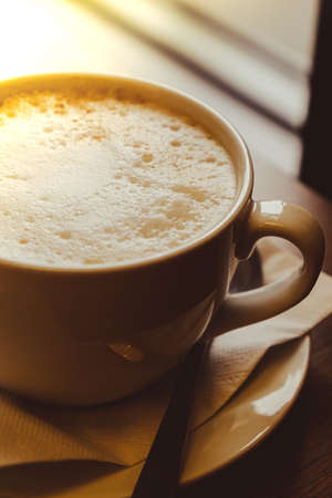 Cup of latte cappuccino. Morning coffee aesthetic vibes. breakfast. hard shadows. delicate light. Cappuccino in the morning at cafe. Wallpaper background. Cozy coffee shopの写真素材