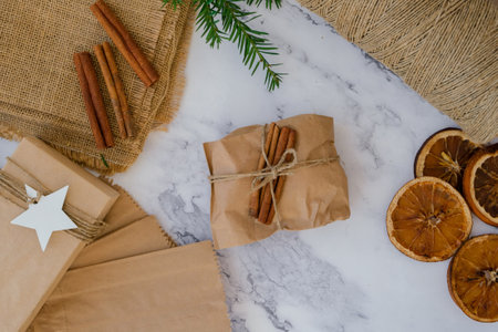 Woman making Box with New Year's gifts, wrapped in craft paper and decorated with cinnamon sticks. Holidays and gifts concept. Handmade Eco friendly alternative green Christmas presents zero waste Sustainable lifestyle Top viewの写真素材