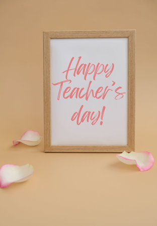 Wooden frame with text HAPPY TEACHERS DAY on paper blank and delicate pink rose petals on beige background. Romantic pastel pink rose flowers. Neutral earth tones. Greeting card holidayの写真素材