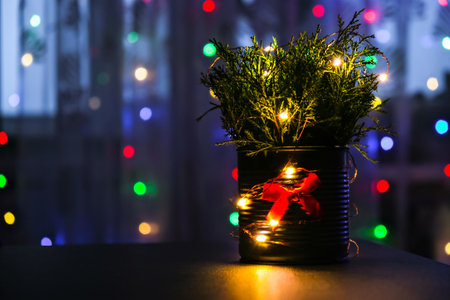 Christmas decorated eco christmas tree in metal jar with bokeh lights on background in living room...
