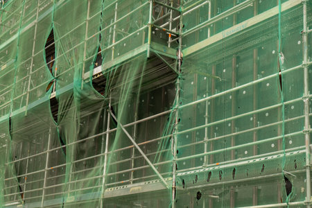 Construction site with unfinished residential building outdoors covered with protective fence....