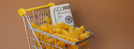 Shopping trolley cart Filled With Pasta with 20 US dollar paper money banknote on Beige background. Copy space for your text. Food and groceries shopping price increase, Rising food cost food crisis inflation concept. Online shopping, buy mall market shop consumerの写真素材