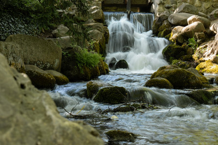 Waterfall cascade in Olivia public park Gdansk Poland. River waterfall falls from cliff and trees....