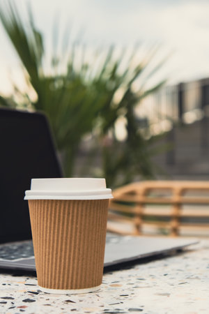 Mock up of modern laptop at table in beach resort. Remote Freelancer's place of work. Study and work online. Remote business education. Concept of webinar. E-learning Workstation Take away recycling coffee from paper cup. Co-Working Space. Coffee break Technology in Life Copy spaceの写真素材