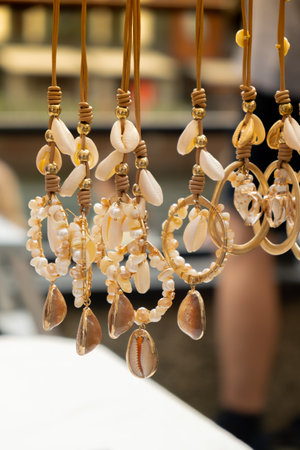 Jewelery showcase sea decorations on street market. Woman choosing decorations on local street market in Gdansk, Poland. Female tourist is choosing souvenirs in street shop and looking at color bracelets. Candid Local souvenir concept. Tourist travel destinationsの写真素材