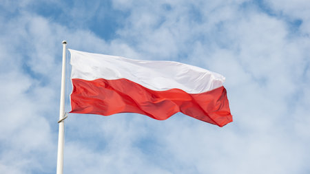 Flag of Poland waving at wind against beautiful blue sky. Polish flag White and red flutters on blue sky. National flag of Polandの写真素材