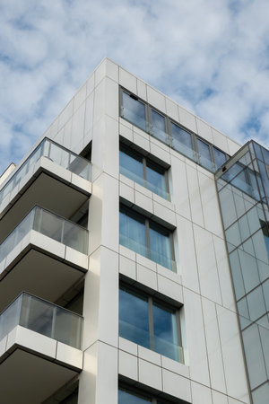 Modern office building exterior with glass facade on clear sky background. Transparent glass wall of...