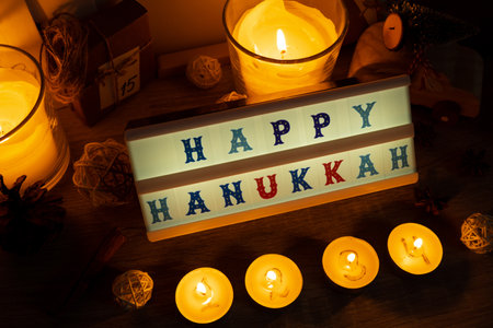 Four Candles with advent calendar Lightbox with text HAPPY HANUKKAH Traditional Burning Christmas Wax Candles with numbers counting down for Christmas. Beautiful Advent At Home. Festive Candlelight And Dark Background. Christmas eveの写真素材