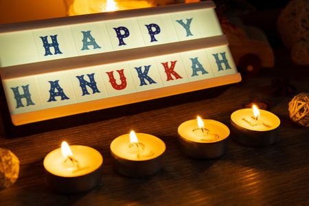 Four Candles with advent calendar Lightbox with text HAPPY HANUKKAH Traditional Burning Christmas Wax Candles with numbers counting down for Christmas. Beautiful Advent At Home. Festive Candlelight And Dark Background. Christmas eveの写真素材