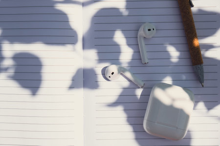 Paper notebook with wireless headphones. Mockup coffee break. Audio healing, sound therapy wellness...